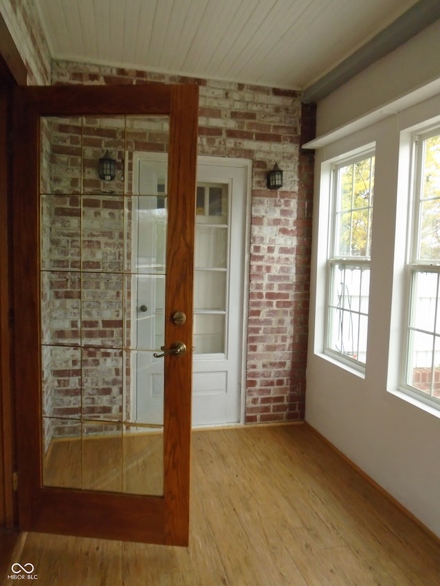 empty room featuring wood-type flooring, wooden ceiling, and brick wall