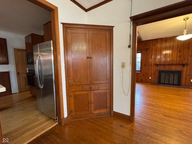 kitchen with light hardwood / wood-style flooring, pendant lighting, vaulted ceiling, black appliances, and ornamental molding