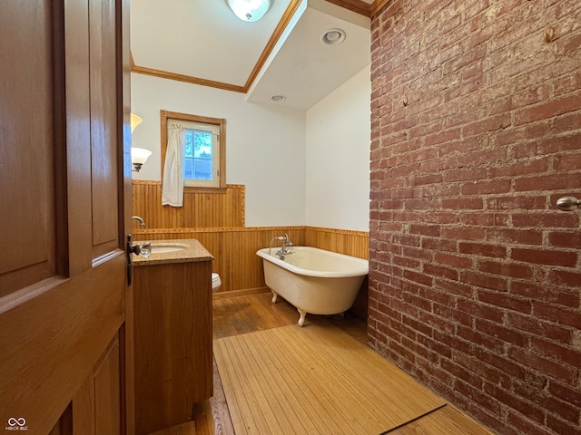 bathroom with crown molding, a washtub, wood-type flooring, and brick wall