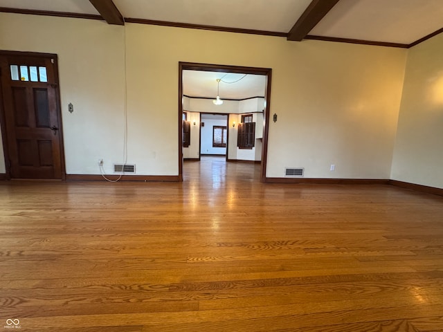 spare room featuring crown molding, hardwood / wood-style floors, and beamed ceiling