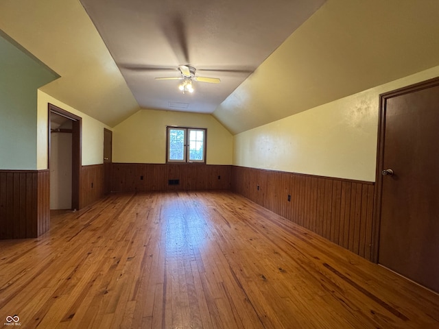 bonus room with ceiling fan, wood walls, light hardwood / wood-style flooring, and vaulted ceiling