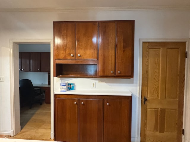 kitchen featuring built in desk, light hardwood / wood-style floors, and ornamental molding