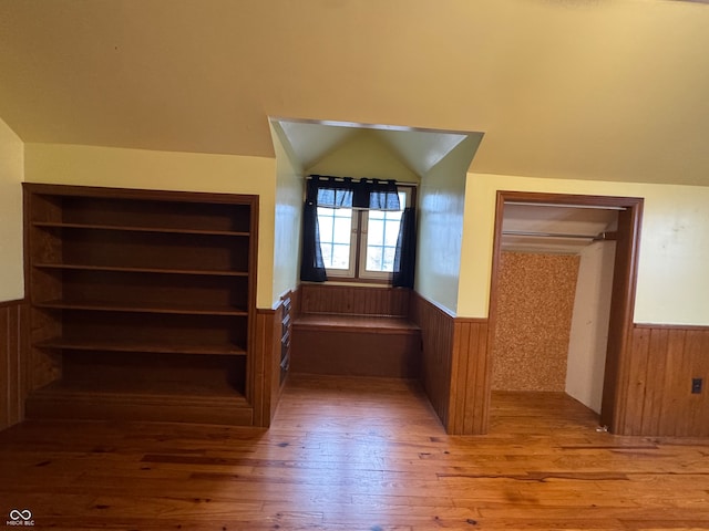 staircase with hardwood / wood-style flooring, lofted ceiling, wood walls, and built in features