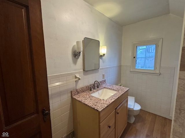 bathroom with hardwood / wood-style floors, vanity, tile walls, and toilet