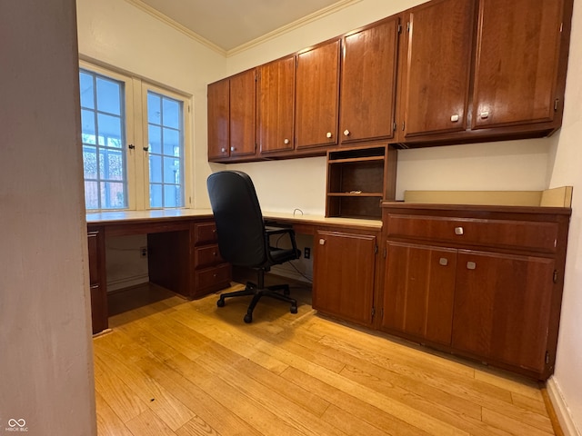 home office featuring crown molding, built in desk, and light wood-type flooring