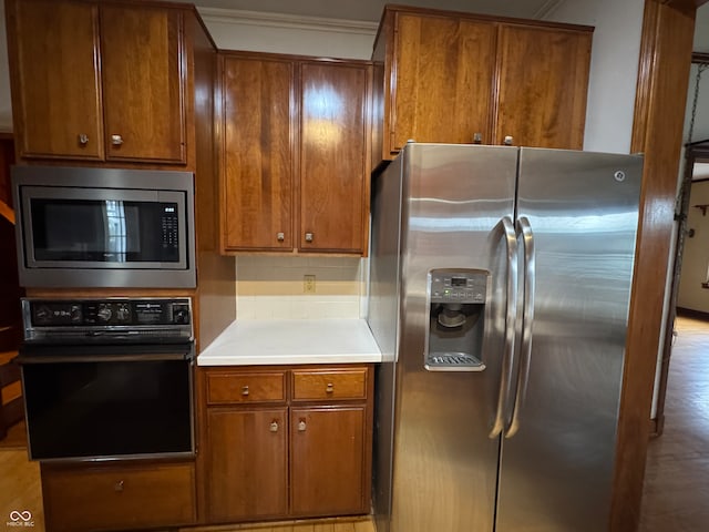 kitchen featuring light hardwood / wood-style floors, crown molding, stainless steel appliances, and tasteful backsplash