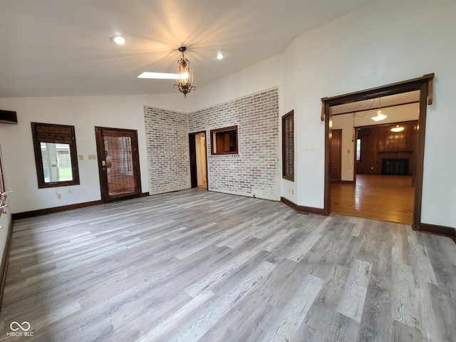 705 W 6th St, Seymour, IN 47274 - unfurnished living room with wood finished floors, baseboards, a chandelier, and high vaulted ceiling