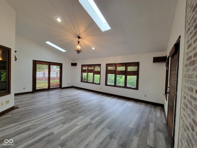 705 W 6th St, Seymour, IN 47274 - unfurnished living room with a skylight, vaulted ceiling, wood finished floors, baseboards, and a chandelier