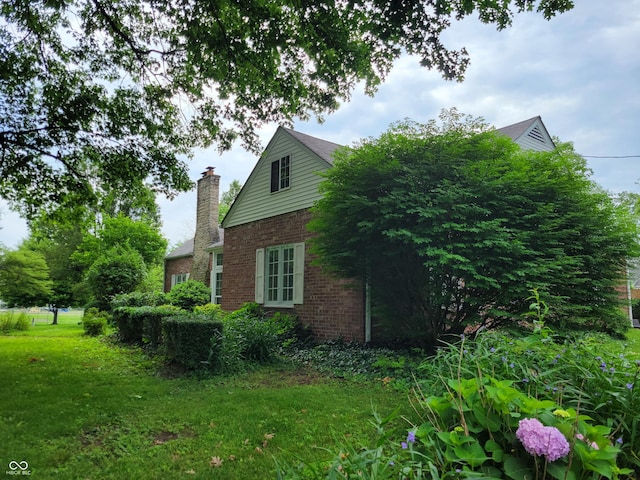 705 W 6th St, Seymour, IN 47274 - view of home's exterior featuring brick siding, a yard, and a chimney