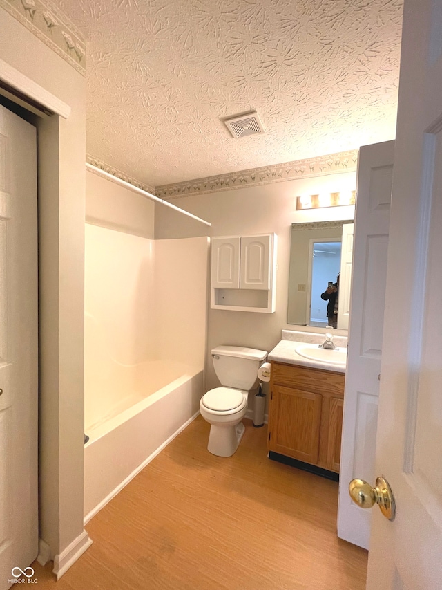 full bathroom with vanity, bathing tub / shower combination, toilet, a textured ceiling, and wood-type flooring