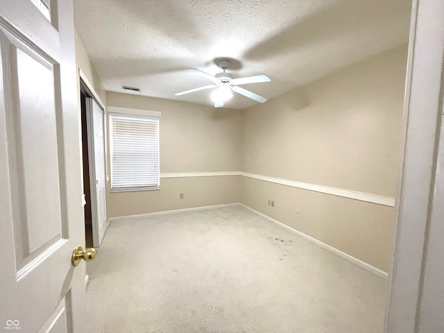 unfurnished bedroom featuring a textured ceiling, ceiling fan, and light carpet