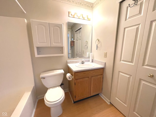 bathroom with a washtub, hardwood / wood-style floors, vanity, and toilet