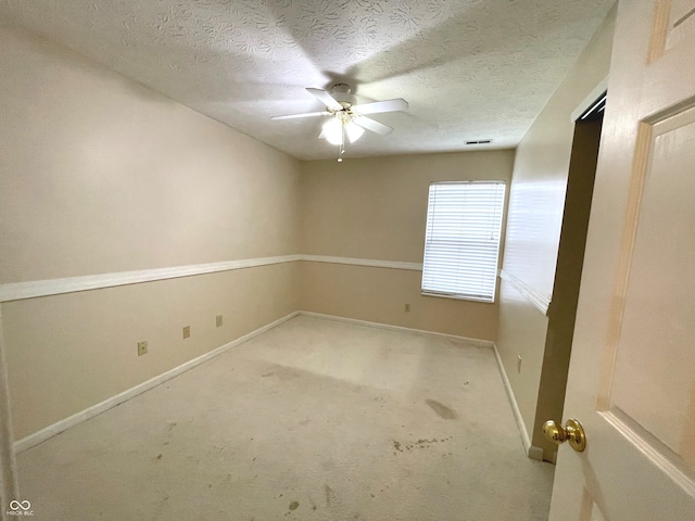 carpeted spare room featuring ceiling fan and a textured ceiling