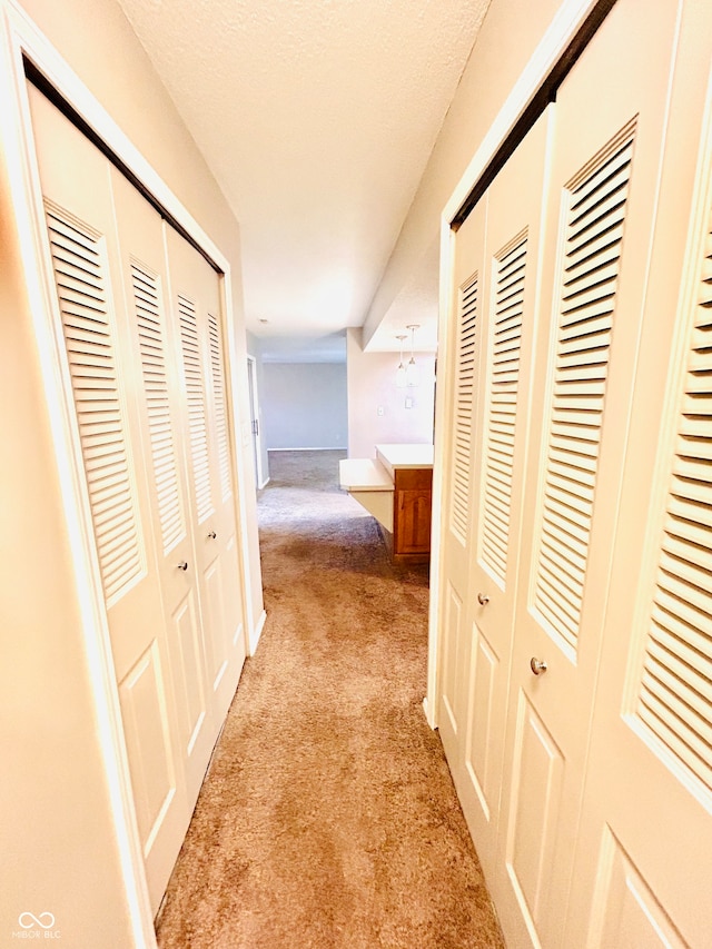 hallway featuring light carpet and a textured ceiling