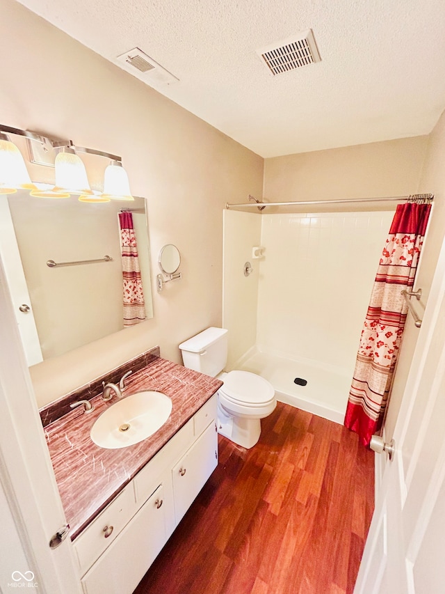 bathroom featuring a shower with curtain, hardwood / wood-style floors, a textured ceiling, toilet, and vanity