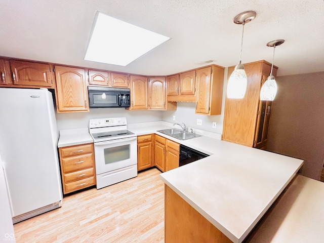 kitchen featuring pendant lighting, black appliances, sink, light wood-type flooring, and kitchen peninsula