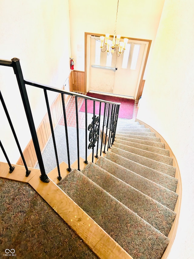 stairs with a chandelier, a towering ceiling, and carpet flooring