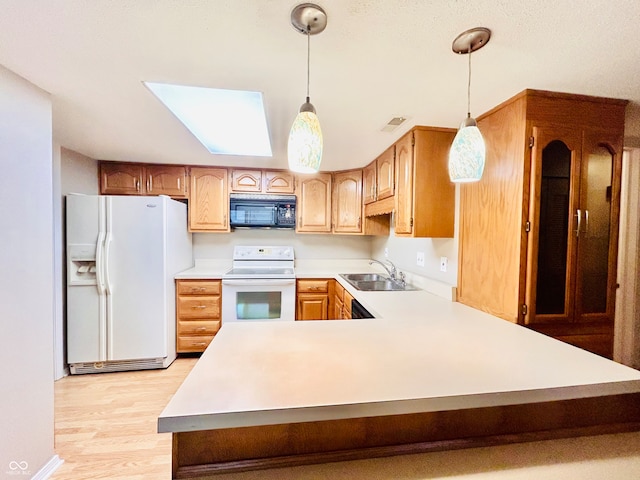 kitchen with white appliances, sink, hanging light fixtures, light hardwood / wood-style flooring, and kitchen peninsula