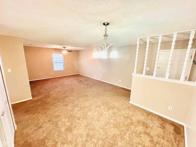 spare room with carpet flooring, ceiling fan with notable chandelier, and a textured ceiling