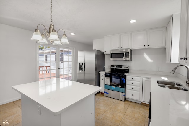 kitchen featuring appliances with stainless steel finishes, a kitchen island, sink, white cabinetry, and hanging light fixtures