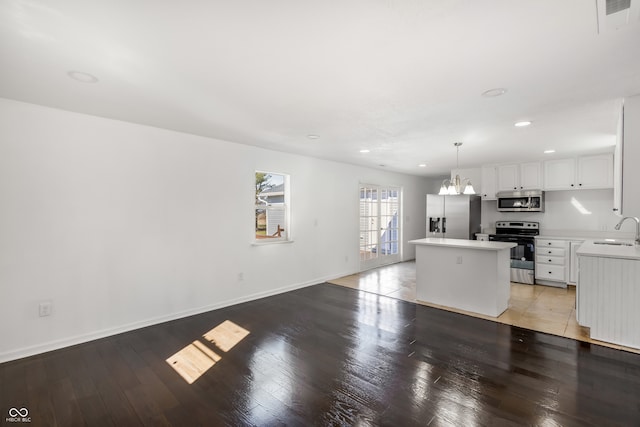 kitchen with hardwood / wood-style floors, pendant lighting, sink, white cabinetry, and stainless steel appliances