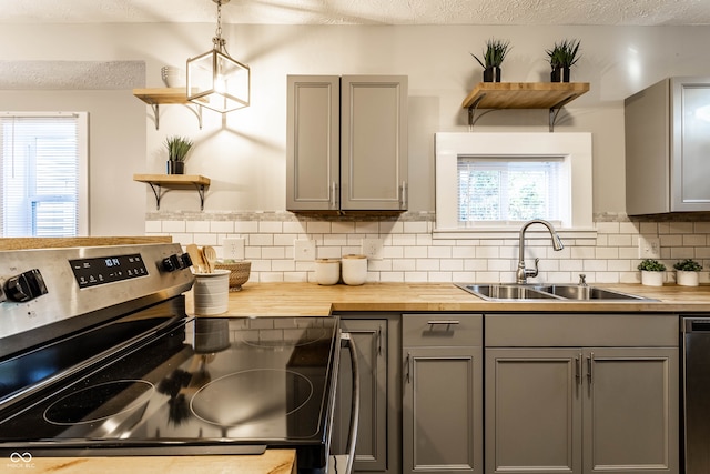 kitchen with pendant lighting, wooden counters, sink, gray cabinets, and appliances with stainless steel finishes