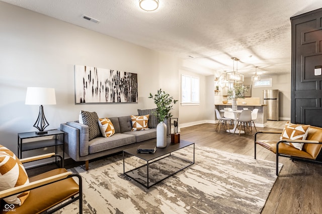 living room featuring hardwood / wood-style flooring, a notable chandelier, and a textured ceiling