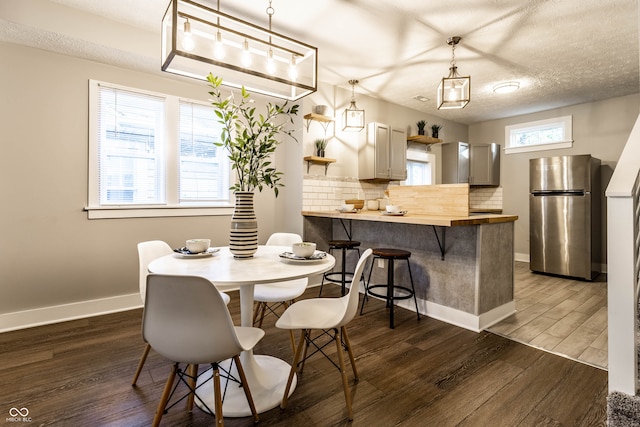 dining space featuring dark hardwood / wood-style floors, a textured ceiling, and a wealth of natural light