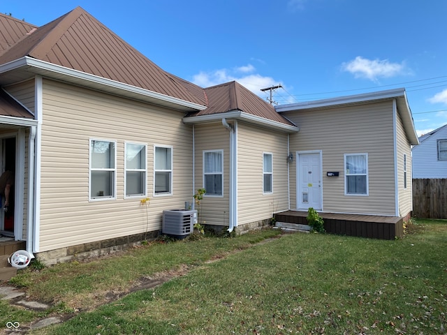 back of property featuring central AC unit and a yard