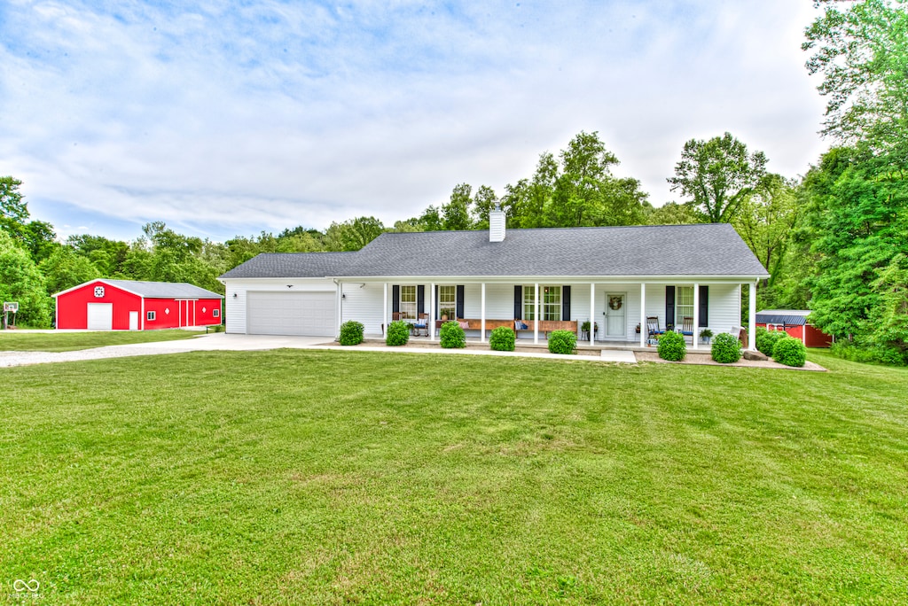 ranch-style house featuring a garage, covered porch, and a front yard