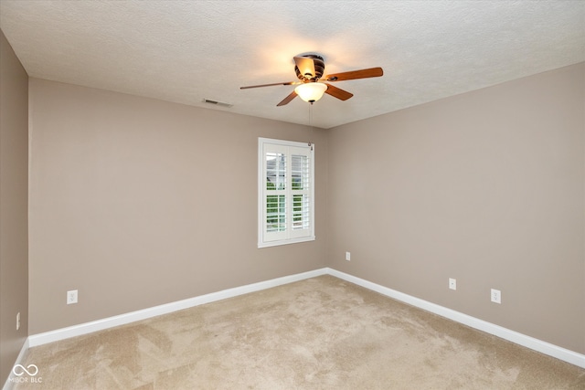 empty room featuring ceiling fan, a textured ceiling, light colored carpet, and baseboards