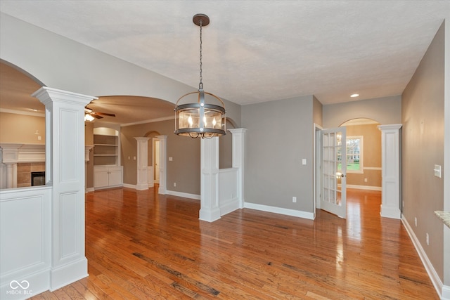 interior space with light wood-style floors, ceiling fan, arched walkways, and baseboards