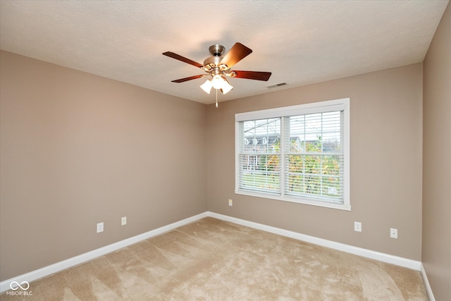 empty room with light carpet, baseboards, visible vents, a ceiling fan, and a textured ceiling