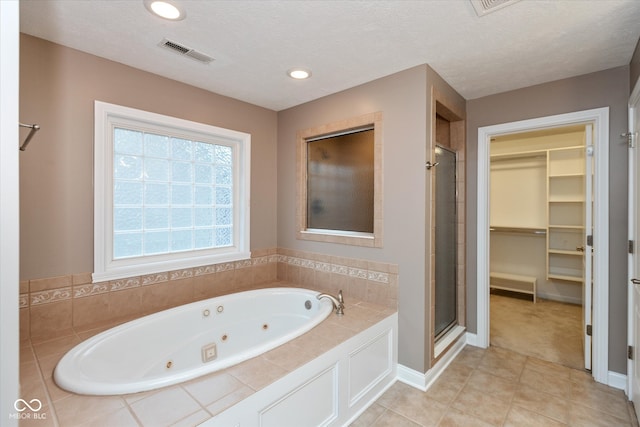 bathroom featuring a stall shower, visible vents, a whirlpool tub, a spacious closet, and a textured ceiling