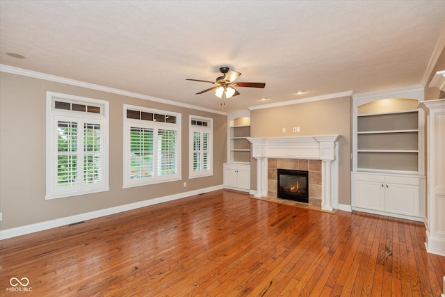 unfurnished living room with a fireplace, visible vents, baseboards, ornamental molding, and wood-type flooring