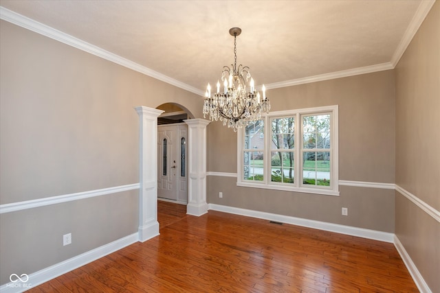 unfurnished dining area featuring visible vents, arched walkways, baseboards, hardwood / wood-style flooring, and ornate columns