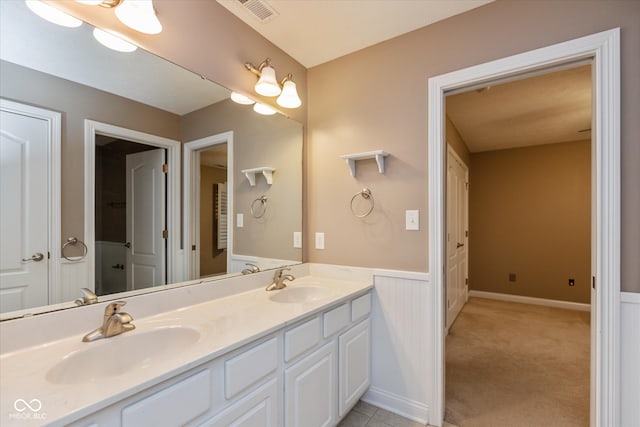 bathroom featuring double vanity, visible vents, a sink, and wainscoting