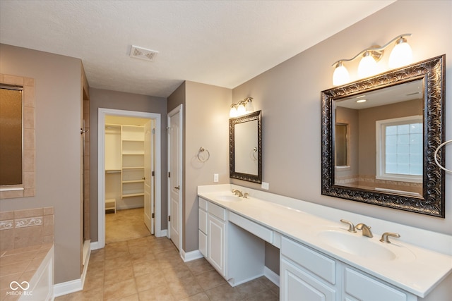 bathroom with double vanity, a sink, visible vents, and a walk in closet