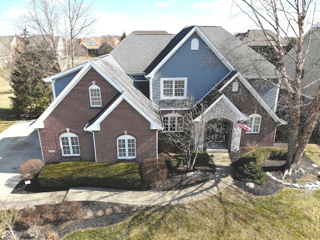 view of front of house featuring stone siding, a front lawn, and brick siding