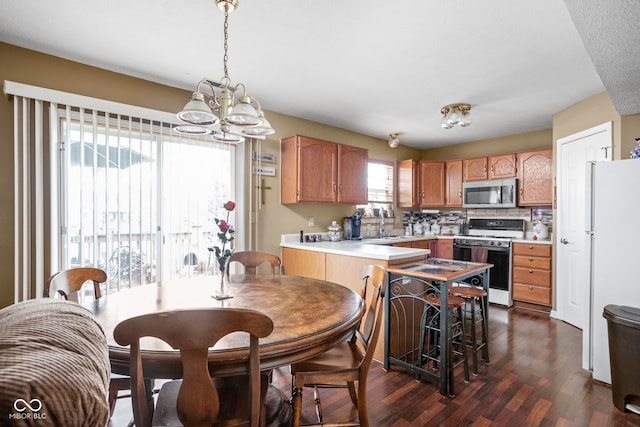 kitchen featuring dark hardwood / wood-style flooring, a notable chandelier, decorative light fixtures, white appliances, and decorative backsplash