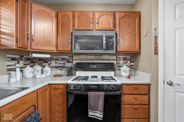 kitchen featuring tasteful backsplash, white gas stove, and sink