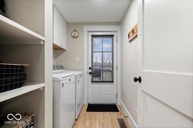 clothes washing area featuring washer and clothes dryer, cabinets, and light wood-type flooring