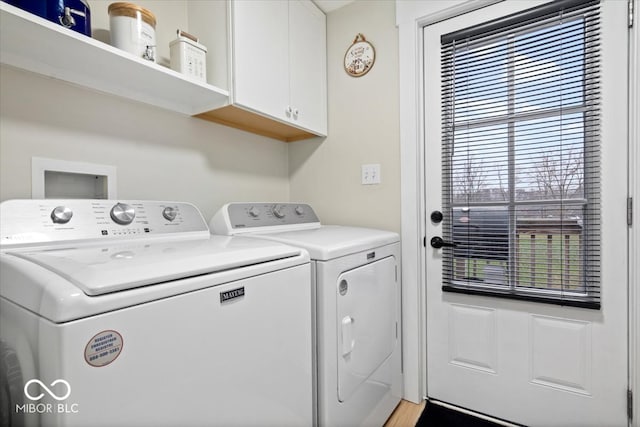 clothes washing area with washer and dryer, cabinets, and light wood-type flooring