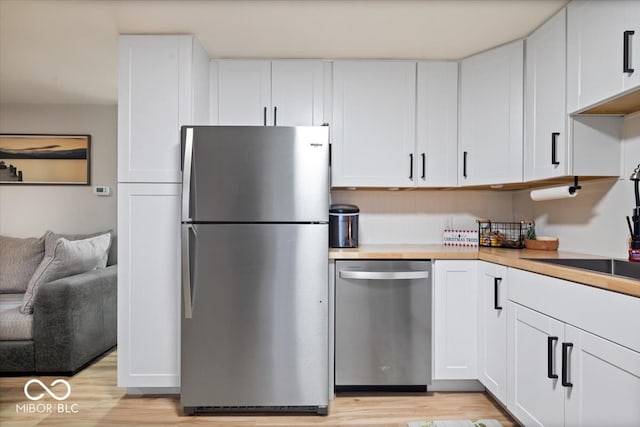 kitchen featuring white cabinets, sink, light wood-type flooring, and stainless steel appliances