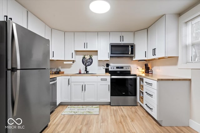 kitchen featuring butcher block countertops, light hardwood / wood-style floors, white cabinetry, and stainless steel appliances