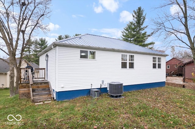 rear view of property with a lawn and central air condition unit