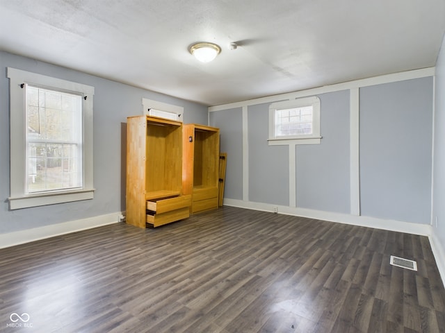 interior space featuring multiple windows, dark wood-type flooring, and a textured ceiling