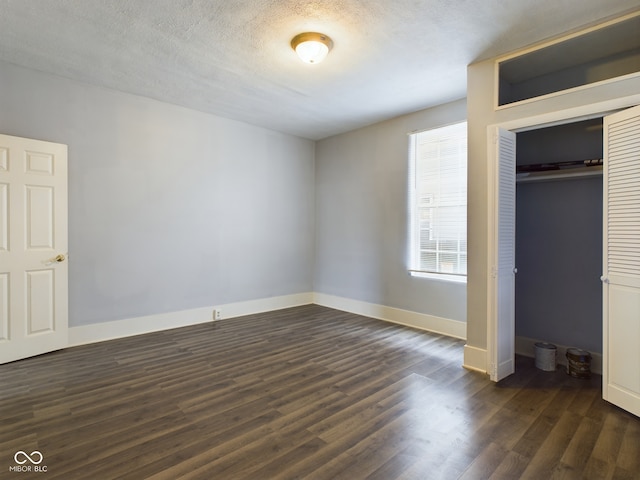 unfurnished bedroom with a textured ceiling, dark wood-type flooring, and a closet