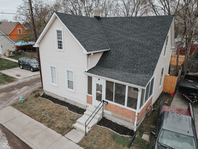 view of front of home featuring entry steps, driveway, a shingled roof, a chimney, and fence