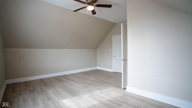 additional living space with light wood-style floors, baseboards, vaulted ceiling, and a ceiling fan